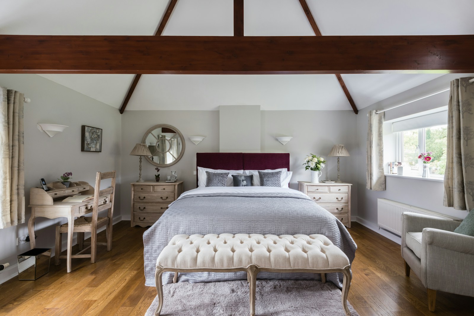 a bedroom with a bed, dresser, chair and mirror